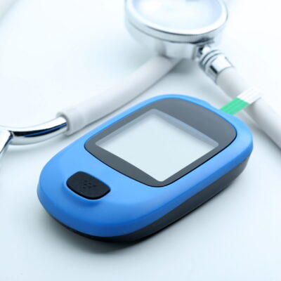 Blood glucose meter and stethoscope on white background